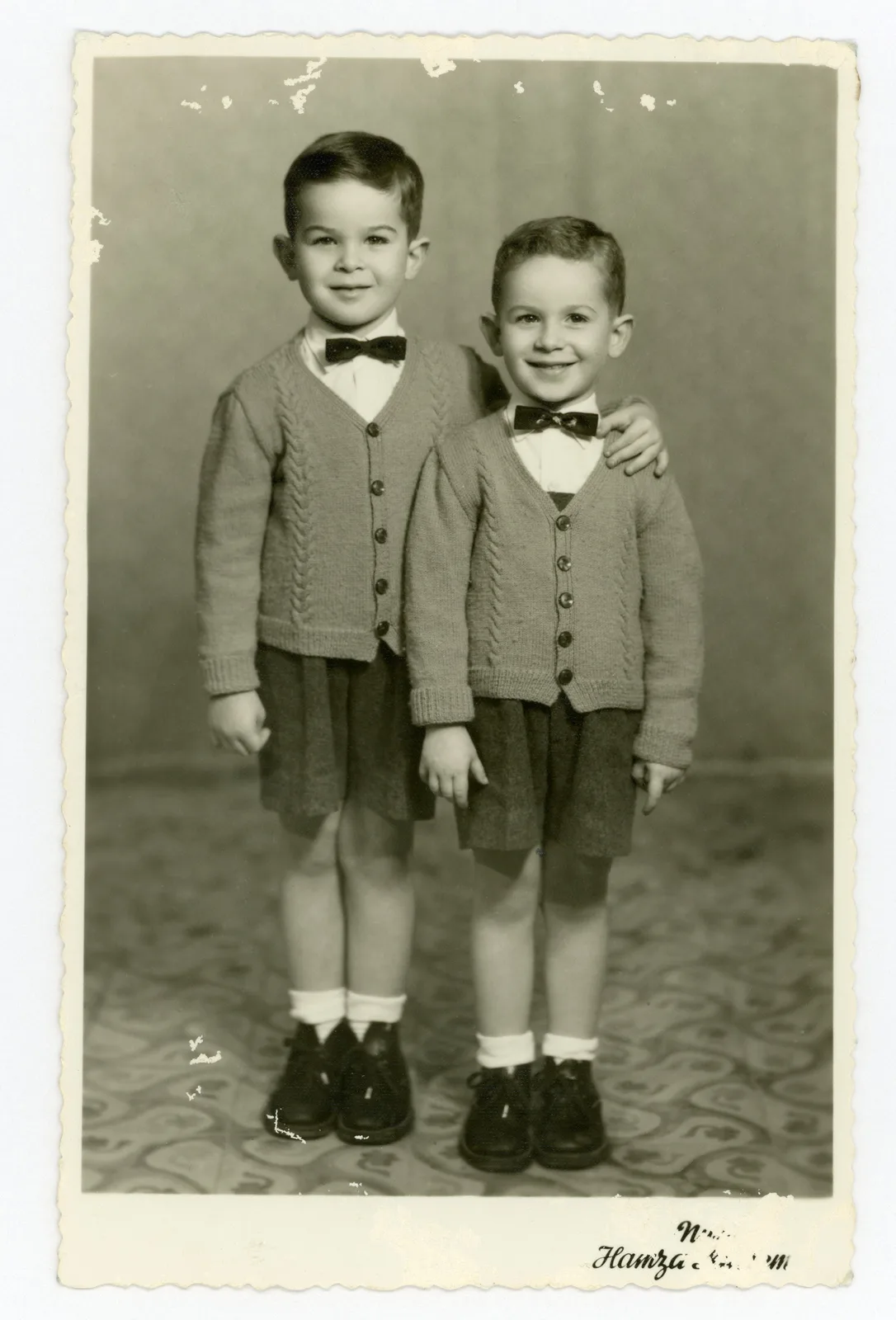 Original: Two young brothers in matching cardigans and bow ties, studio portrait