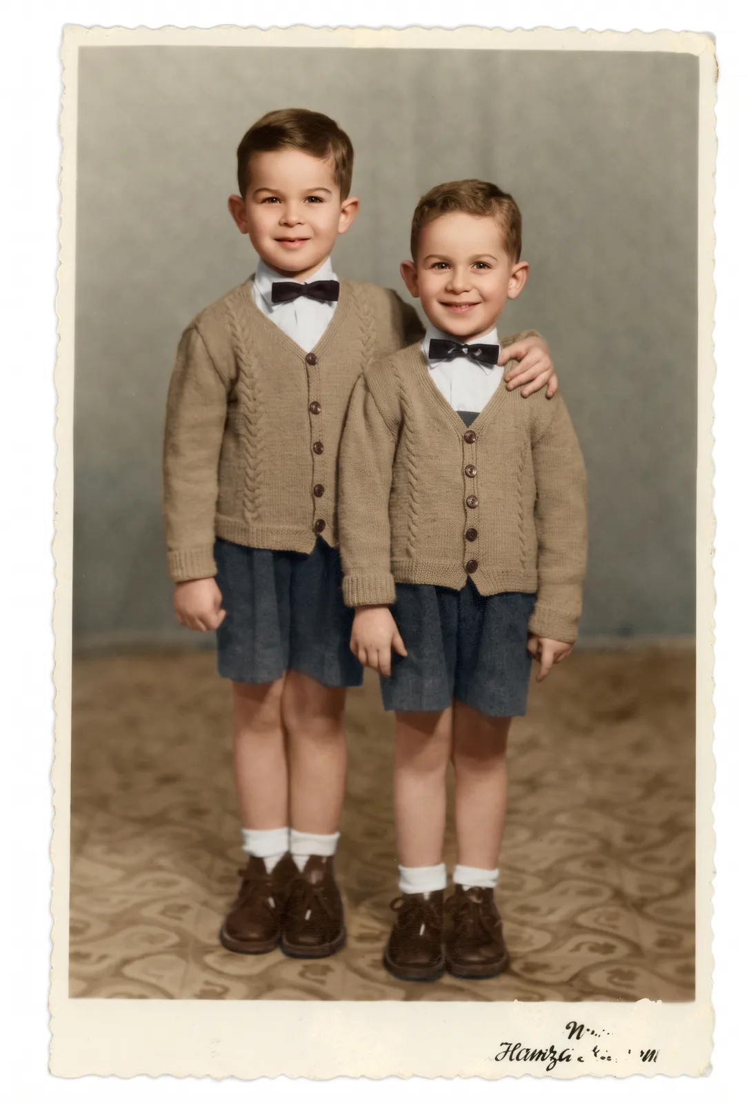 Restored: Two young brothers in matching cardigans and bow ties, studio portrait