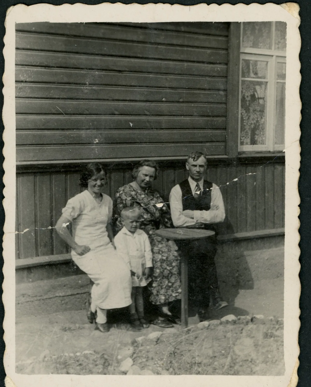 Original: A family seated in front of a wooden house, scratched print